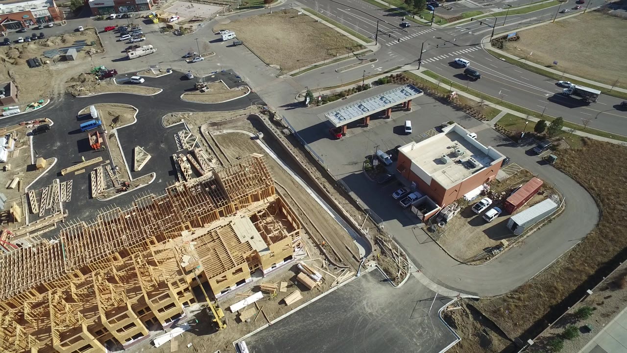 High aerial frame in Hidden Lake, Colorado with rows of exposed lumber framing, an intersection at the top of frame, parking areas, trucks, and no visible people.