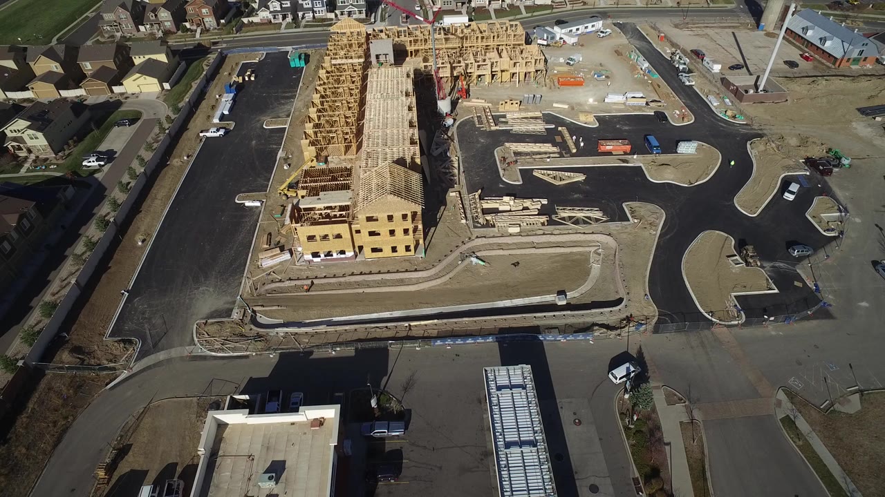 Aerial view of a construction site beside paved parking lots and neighborhood roads.