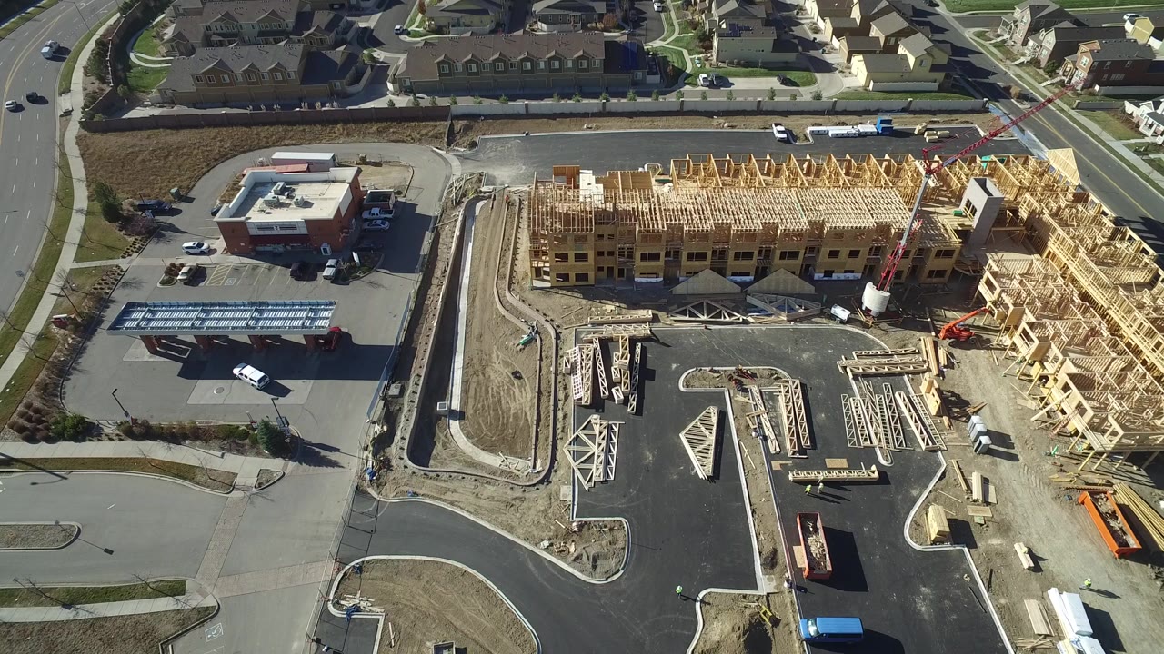 Overhead view of a wood-framed construction site beside roads and houses.