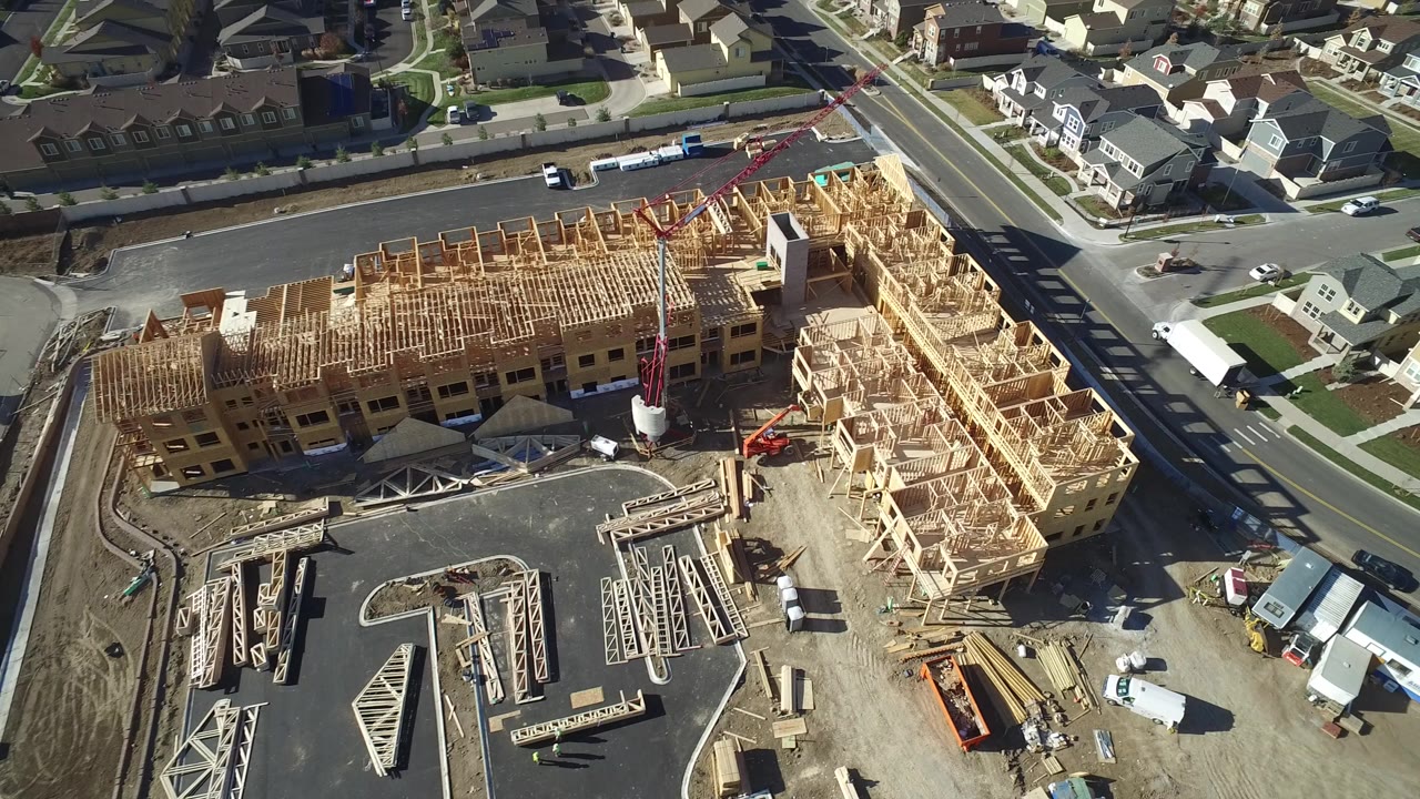 Aerial view of wood-framed residential construction beside suburban streets.