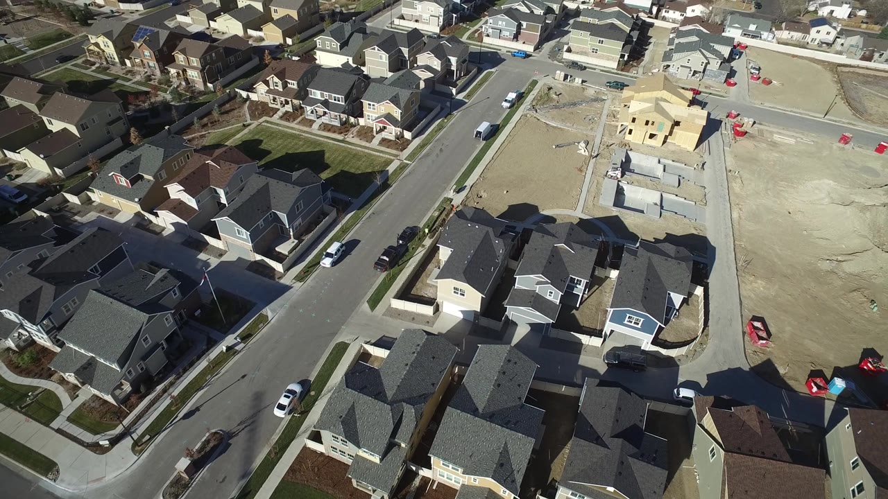 Aerial view in Hidden Lake, Colorado with rooftops in the lower frame, a street through the middle, unfinished foundations to the right, and no visible people.