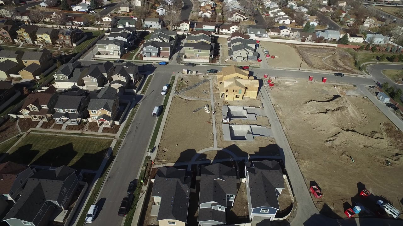 Aerial view of suburban homes beside graded construction lots.