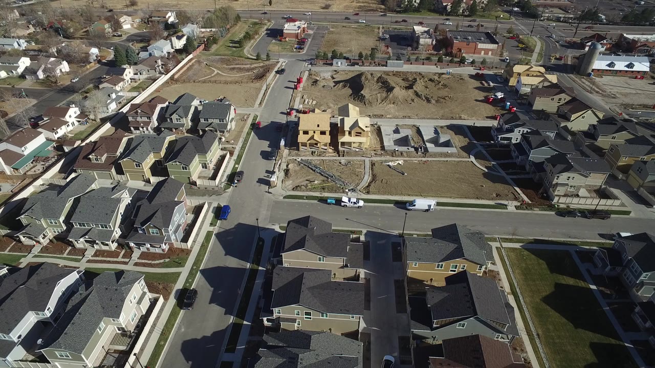 Aerial view of suburban houses, streets, and construction lots.