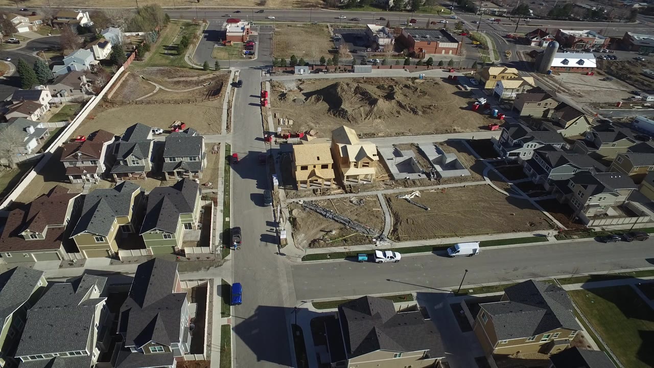 Aerial view of suburban houses, streets, and construction lots.