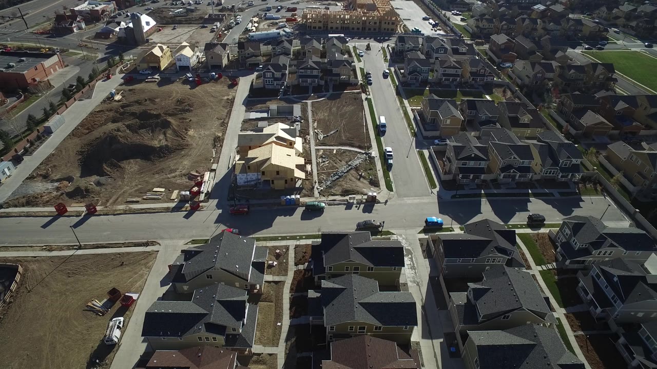 Aerial view of suburban houses, streets, dirt lots, and construction sites.