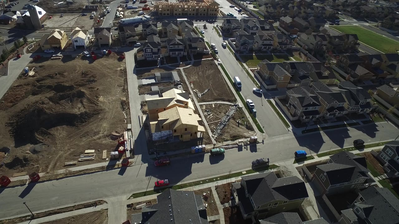High aerial view in Hidden Lake, Colorado with framed houses under construction, graded dirt lots, completed homes, parked vehicles, and no visible people.