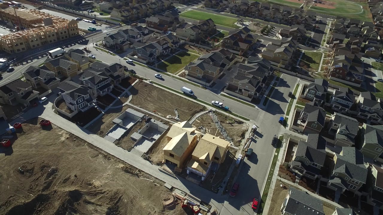 Early overhead view of Hidden Lake, Colorado showing suburban homes, a cross street, framed house construction, bare dirt lots, and no visible people.