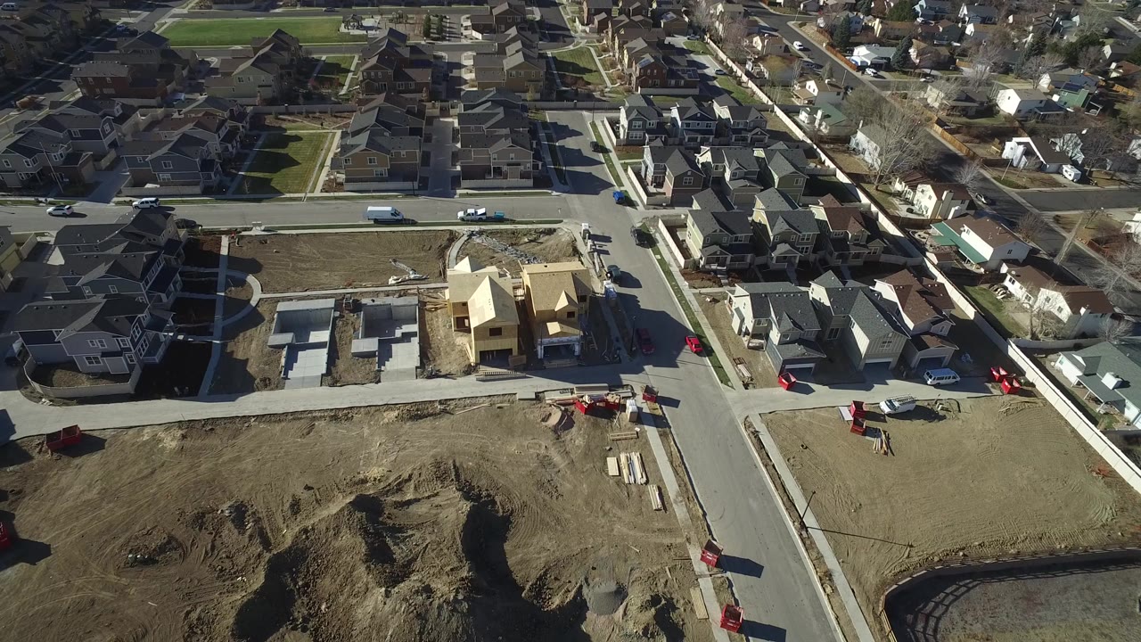 Aerial view of suburban homes, roads, and a construction lot.