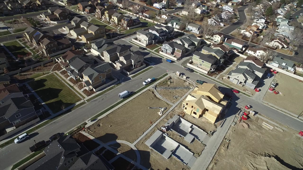 High aerial view of a yellow house under construction in a suburban neighborhood.
