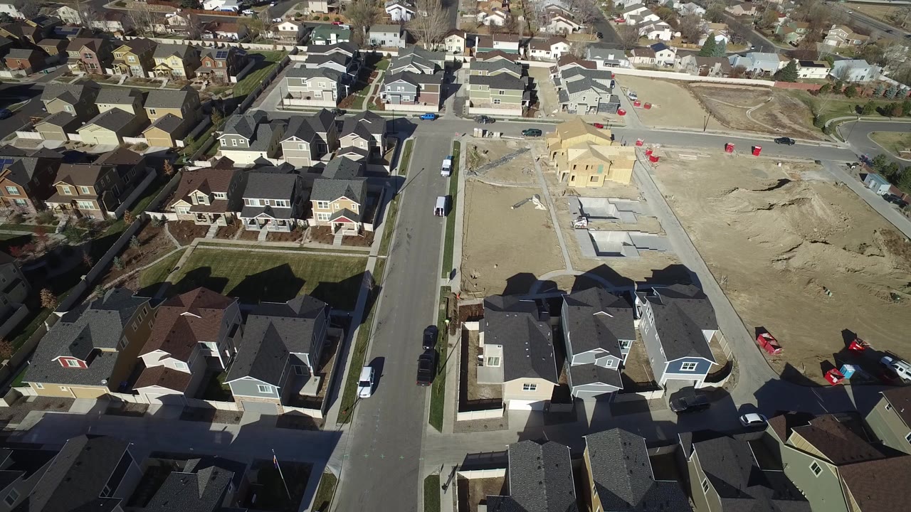 Aerial view of houses, streets, cars, and sandy construction lots.