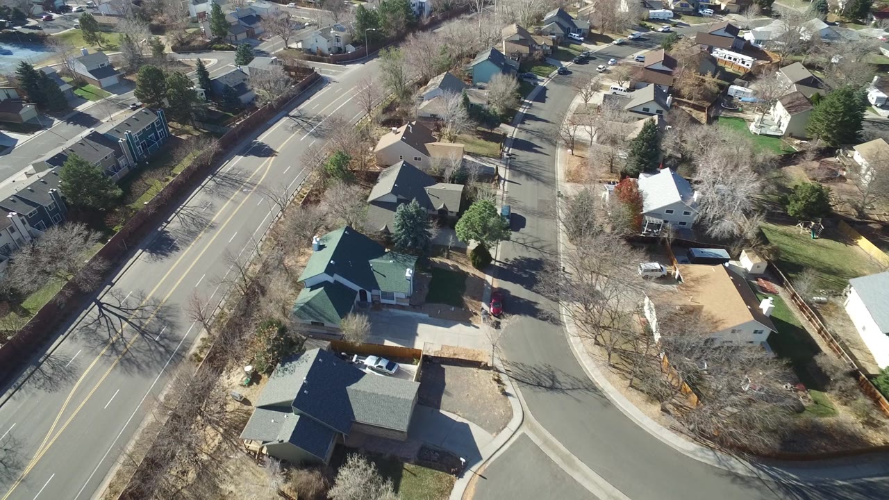 Overhead frame in Hidden Lake, Colorado, with the road bend centered, a green-roofed building near the lower left, houses on both sides, and no visible people.