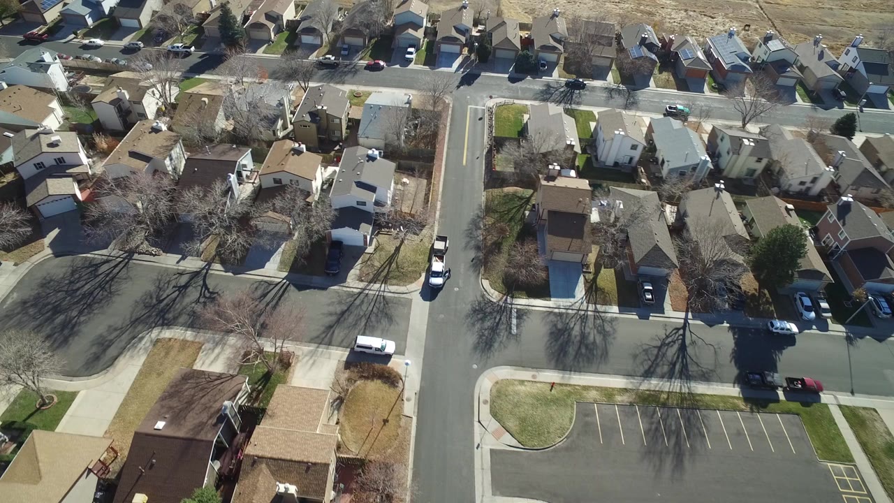Aerial view of houses, streets, parked cars, and winter-brown yards.