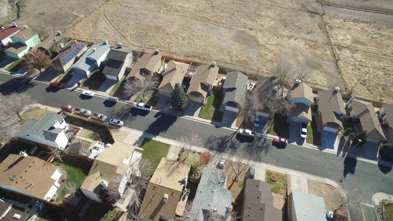 Aerial view of suburban homes beside a dry open field.