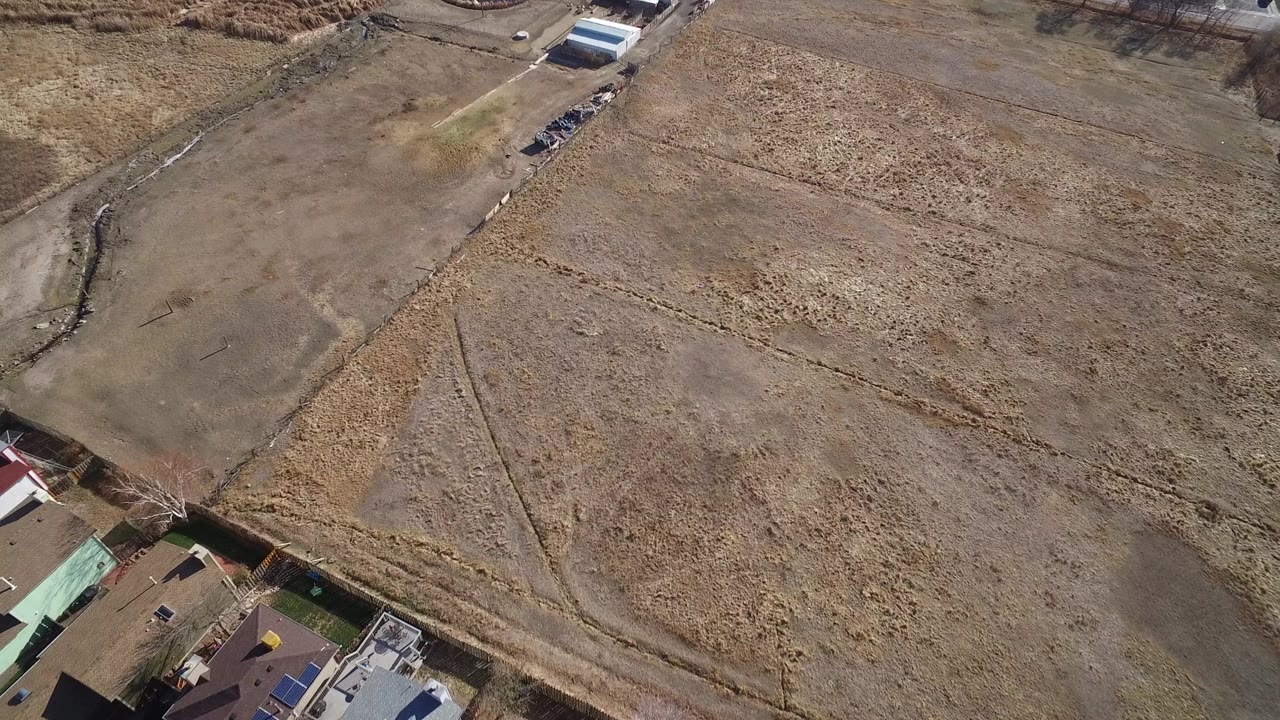 Aerial view of brown fields beside farm buildings and homes