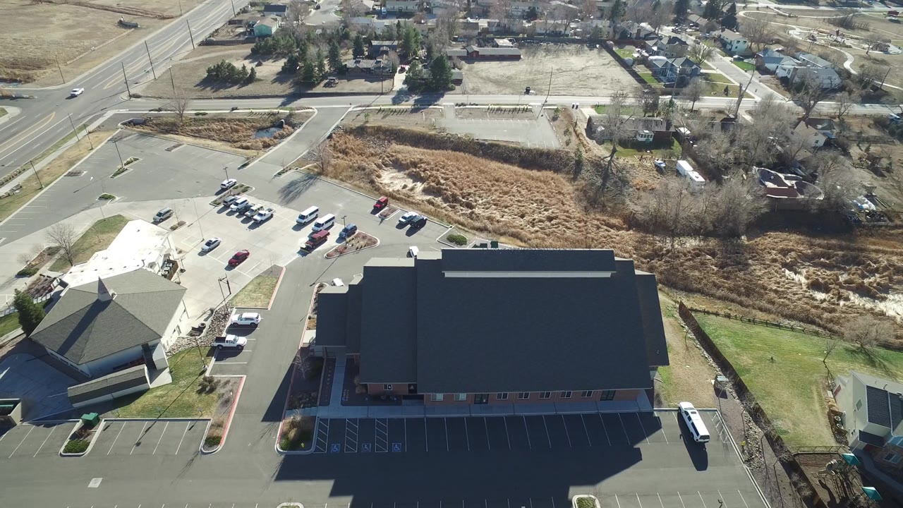 Overhead view of parking areas, two buildings, and a road intersection.