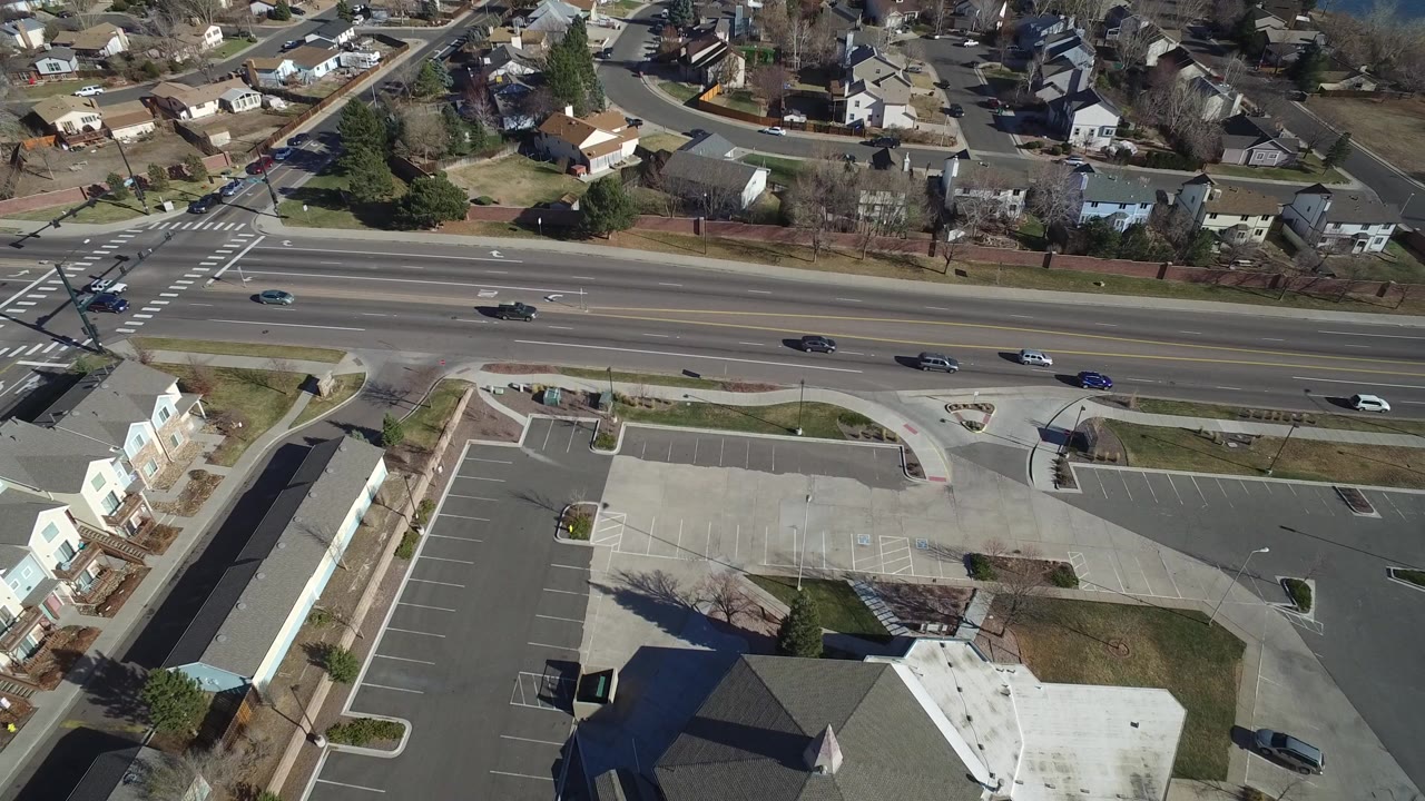 Aerial view of a multilane road, parking lot, and suburban homes.