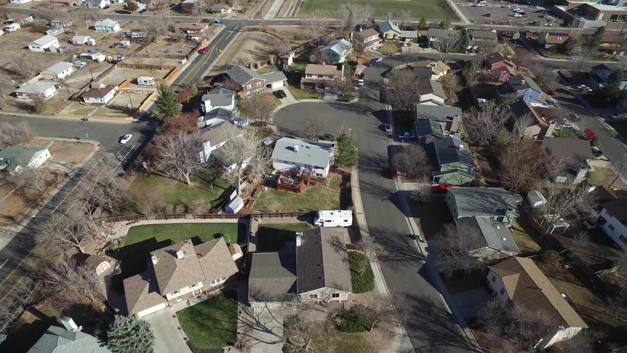 Aerial frame of Hidden Lake, Colorado, with detached homes around a rounded street, a road intersection near the top, dry yards, and no visible people.