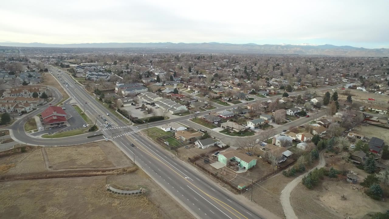 Aerial view of a suburban road intersection and homes under overcast sky.