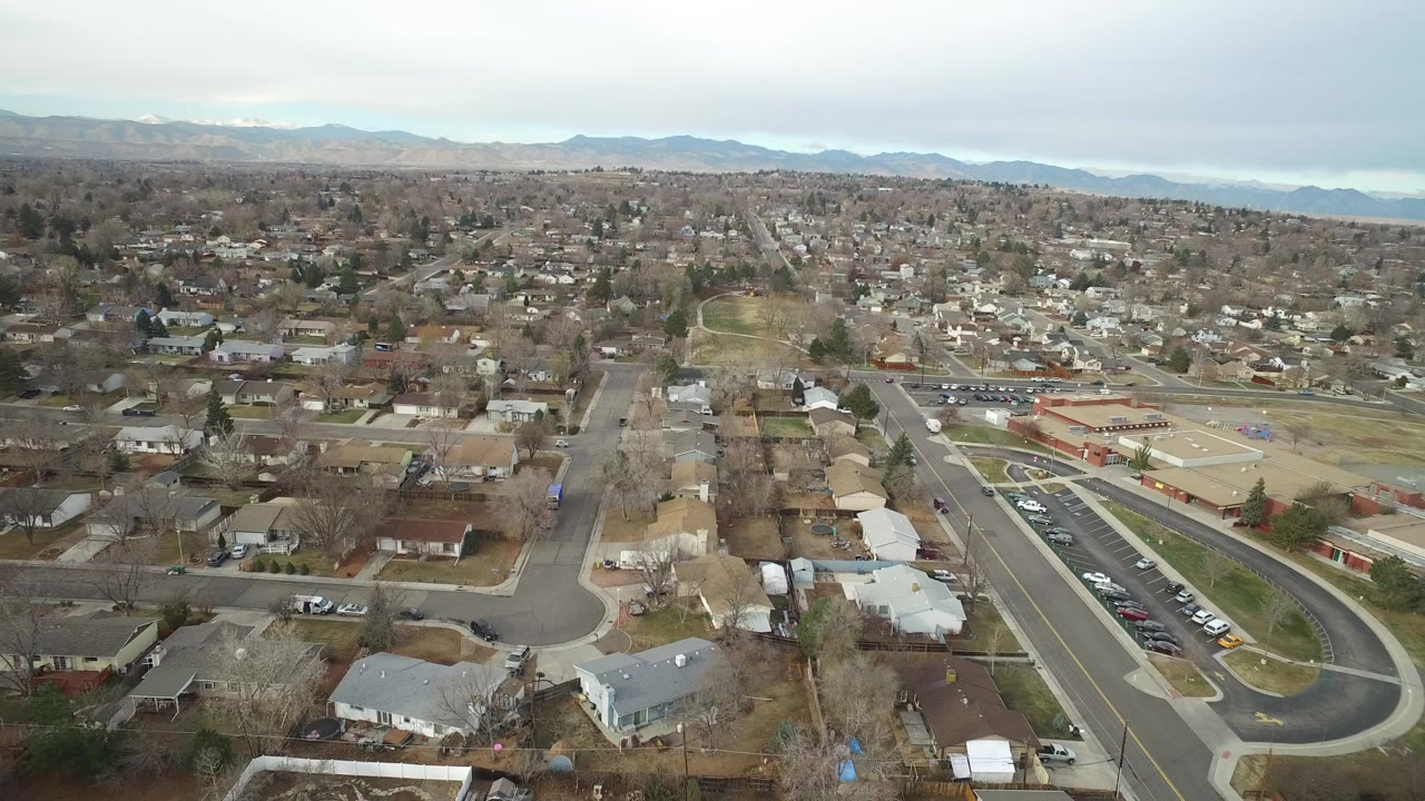 Aerial view over suburban houses, streets, and distant mountains