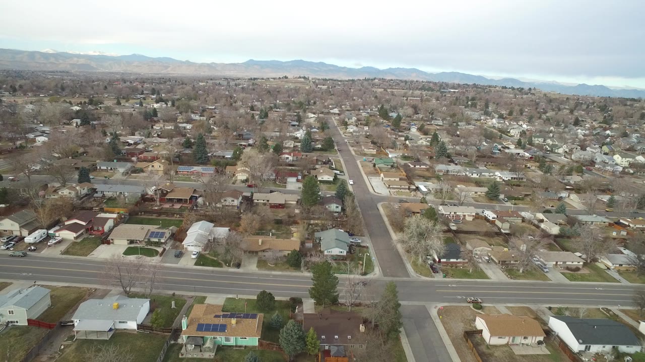 High view of houses, yards, road intersections, and a cloudy mountain horizon