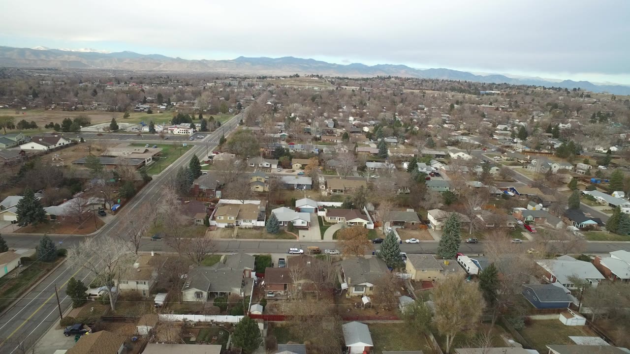 Suburban streets and houses seen from above with mountains beyond.