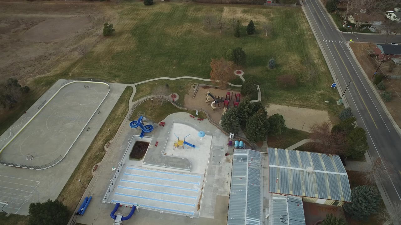 Drone view of empty park amenities beside a large grass field.