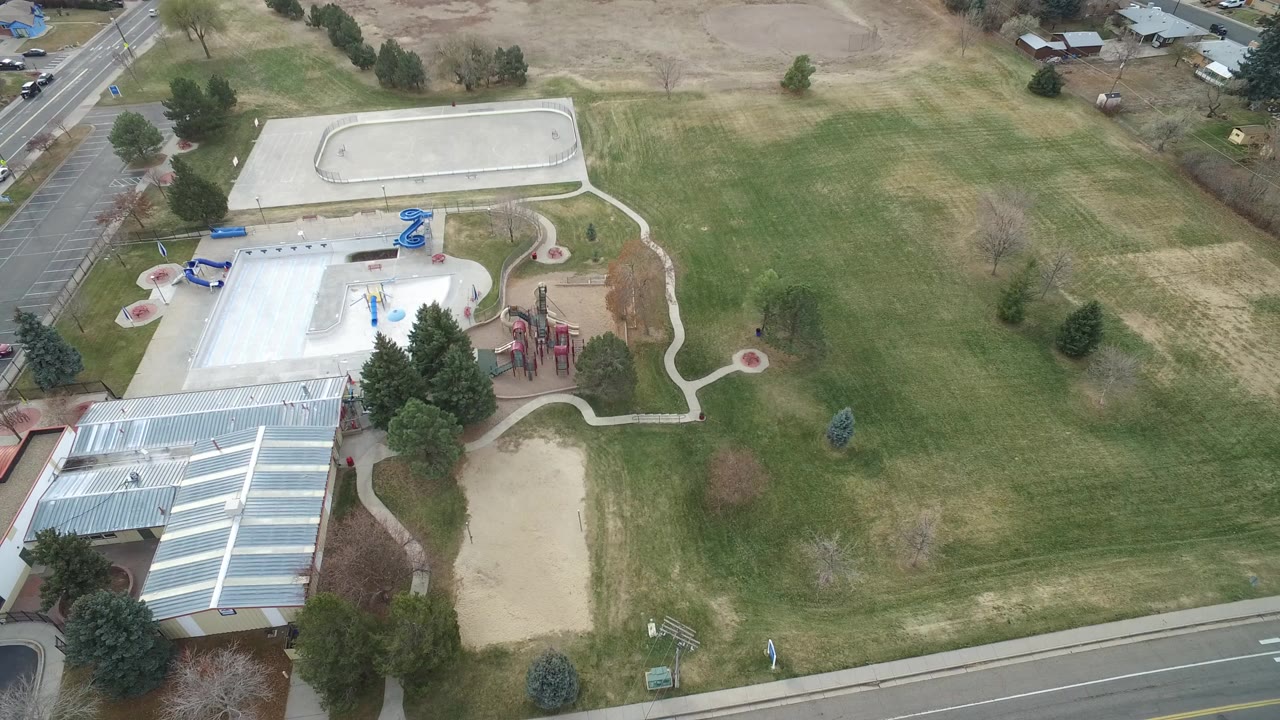 Aerial view of green school grounds with paths, playground equipment, and a covered roof.