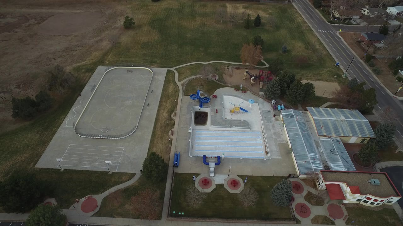 Aerial view of courts, playground structures, grass, paths, and a road.