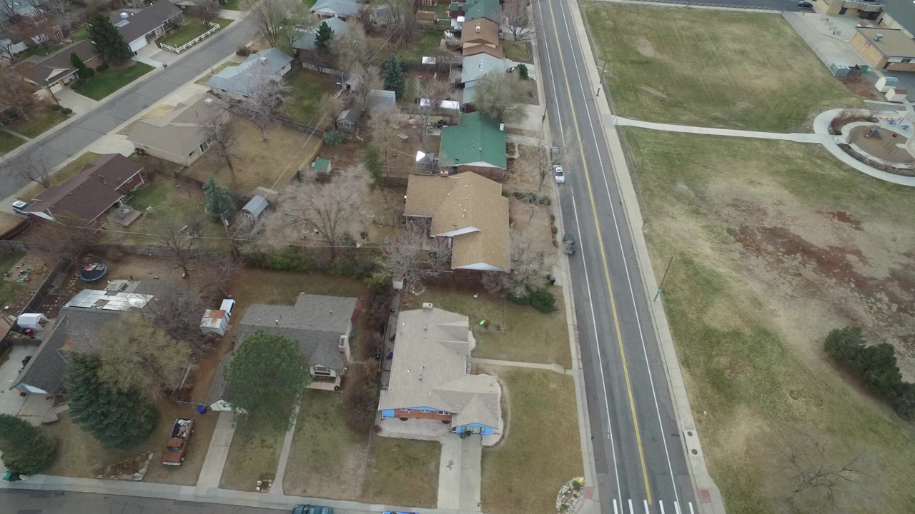 Aerial view of homes beside a wide road and brown lawns.