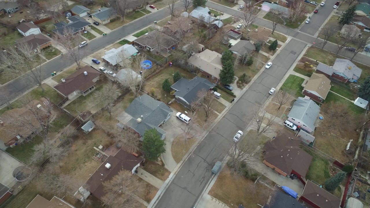 Overhead view of a Westminster, Colorado residential block with single-family homes, parked vehicles, sidewalks, leafless trees, and no visible people.