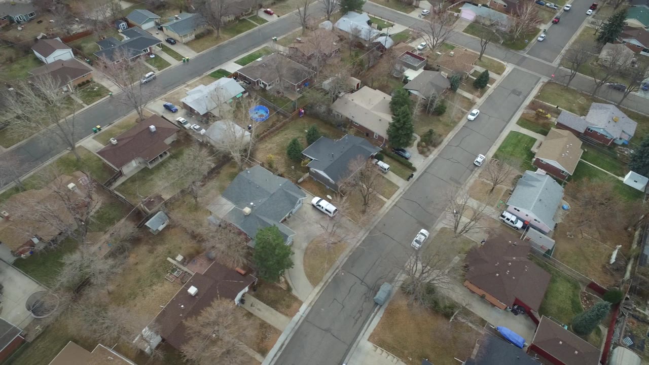 Aerial frame over Westminster homes showing diagonal streets, multiple driveways, parked cars, bare trees, a blue backyard trampoline, and no visible people.