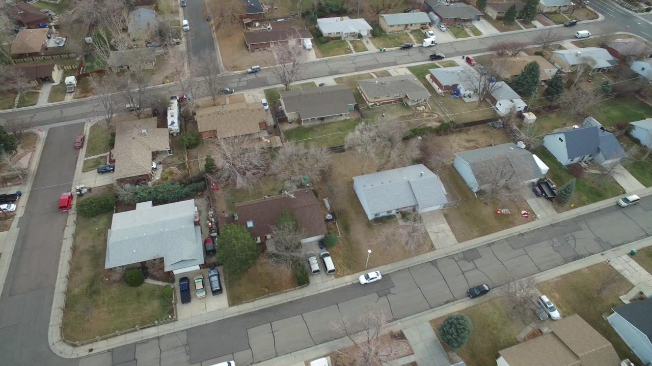 Aerial view of homes, streets, trees, and parked cars.