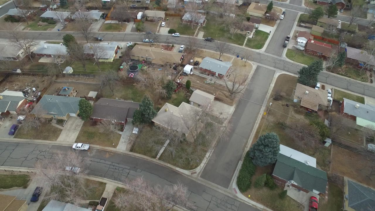 Aerial neighborhood grid with roads, backyards, parked cars, and winter-brown landscaping.