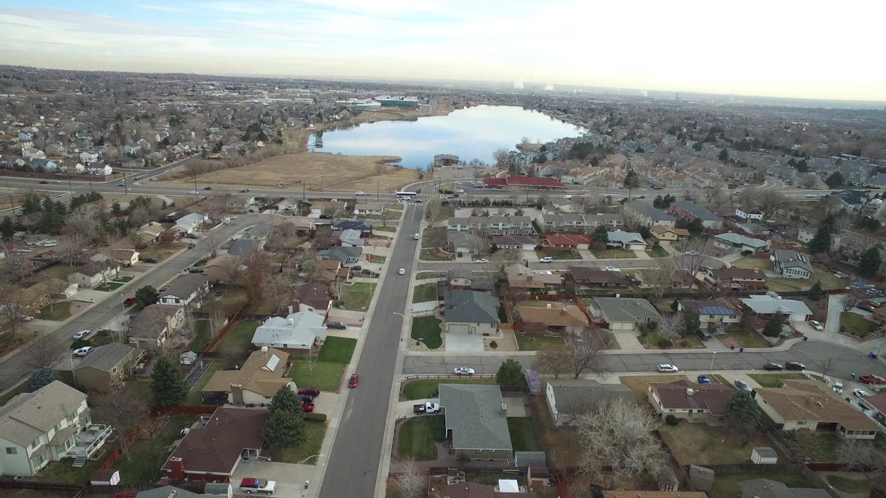 Aerial view over suburban streets and houses toward a lake