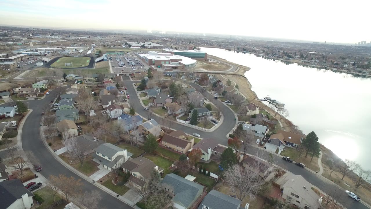 Aerial view of suburban homes beside a bright lake.