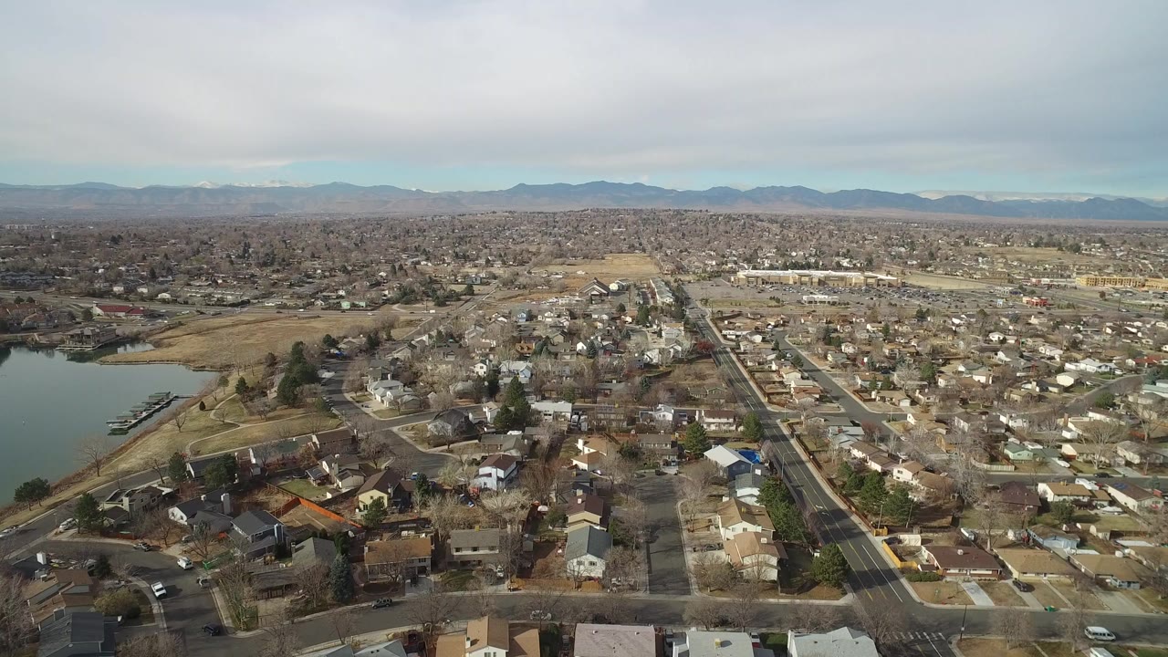 Aerial view of suburban houses beside a lake with mountains in the distance.