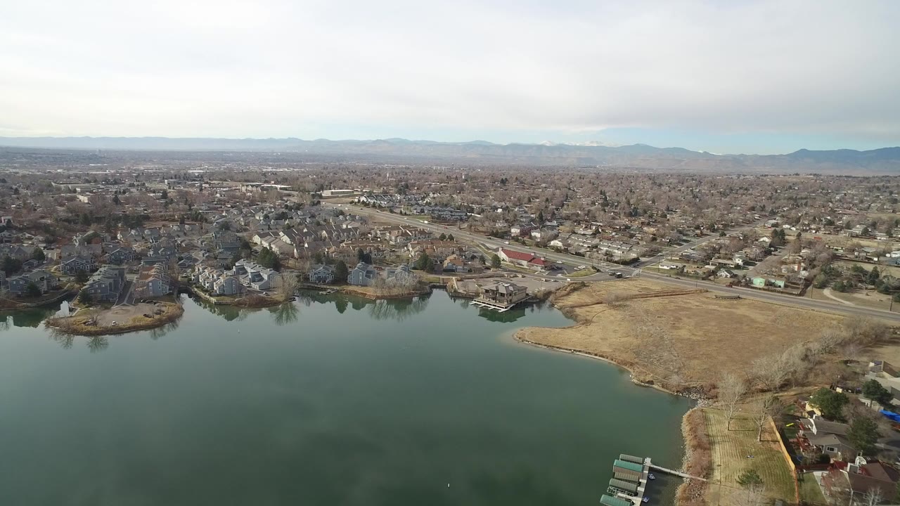 Aerial view over a lake toward suburban homes and roads.