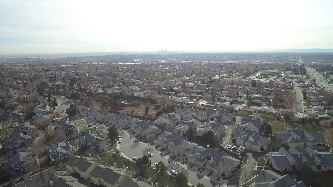 Aerial view over suburban homes and roads under hazy daylight