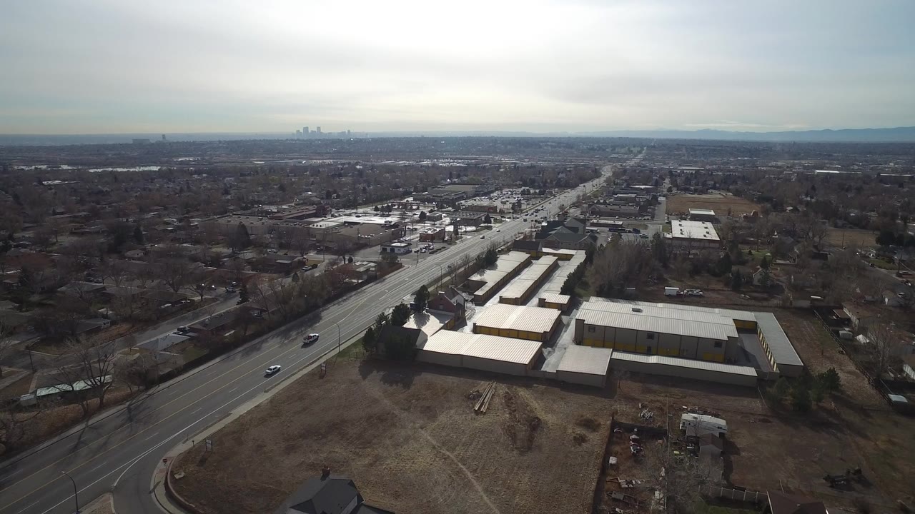Aerial view of industrial buildings beside wide roads and suburban neighborhoods.