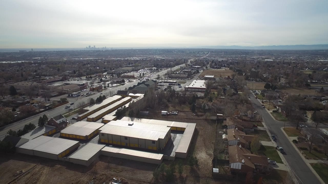 Aerial view over suburban streets and a large light-roofed building complex.
