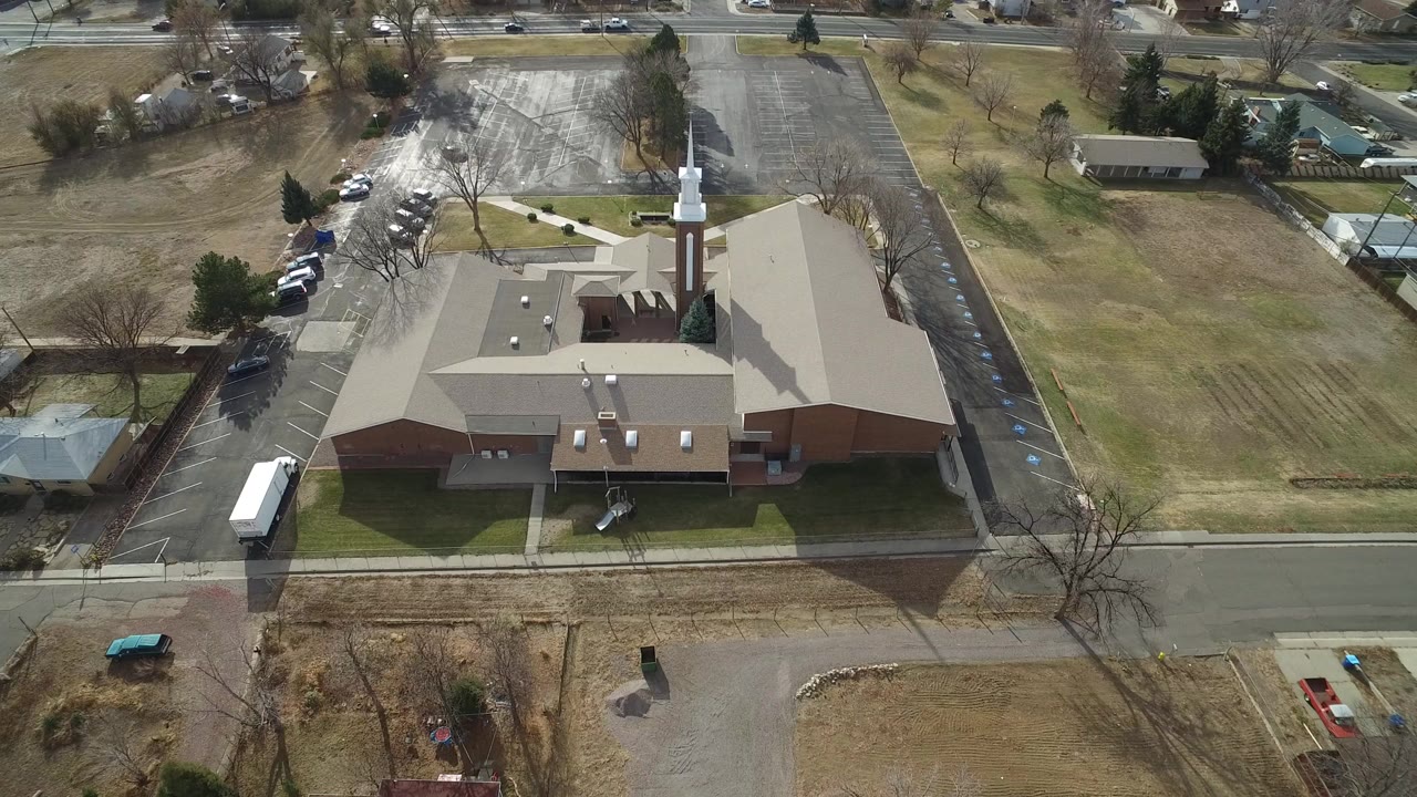 Aerial view of a large church with a white steeple and surrounding streets.