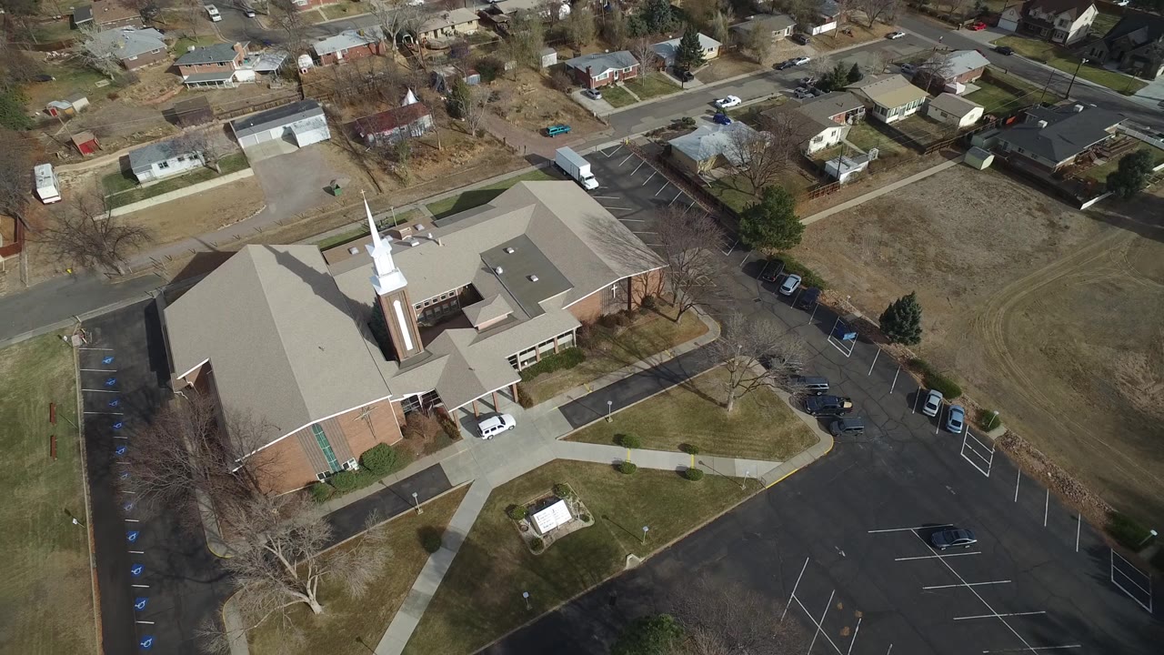 Overhead angle on a church sanctuary beside a large paved parking lot.