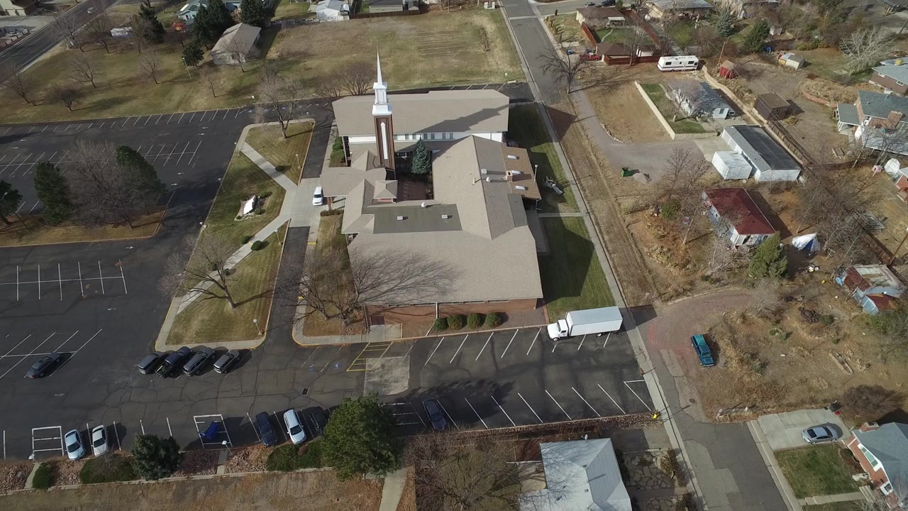 High-angle view of the campus roof, white steeple, parking lot, and neighboring lots.