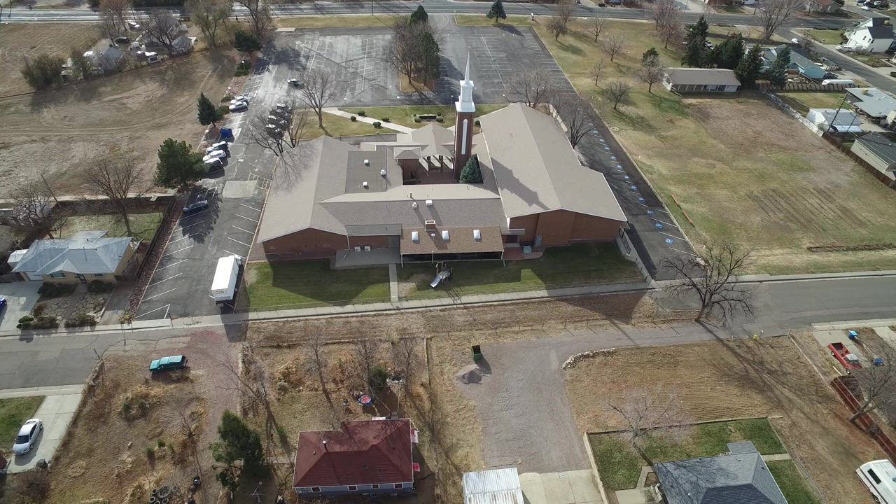 Aerial view of a brick church, nearby homes, streets, and dry lawns.