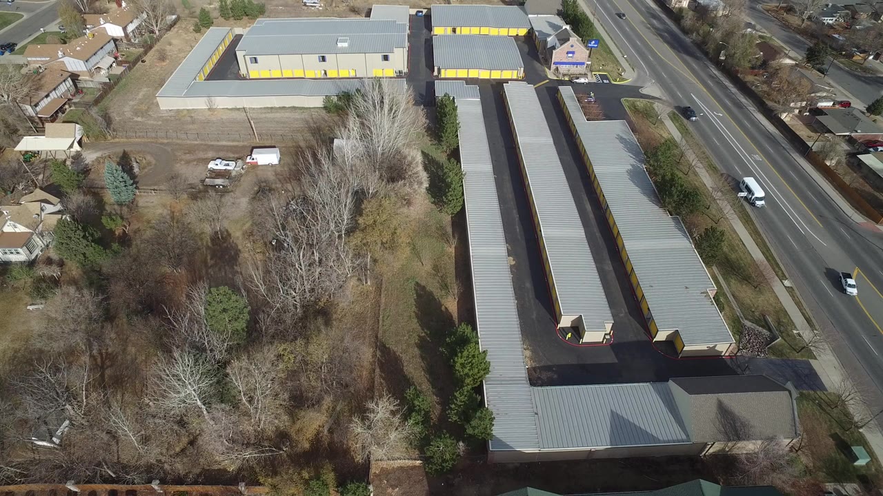 Aerial view of warehouses beside a multi-lane road and trees.