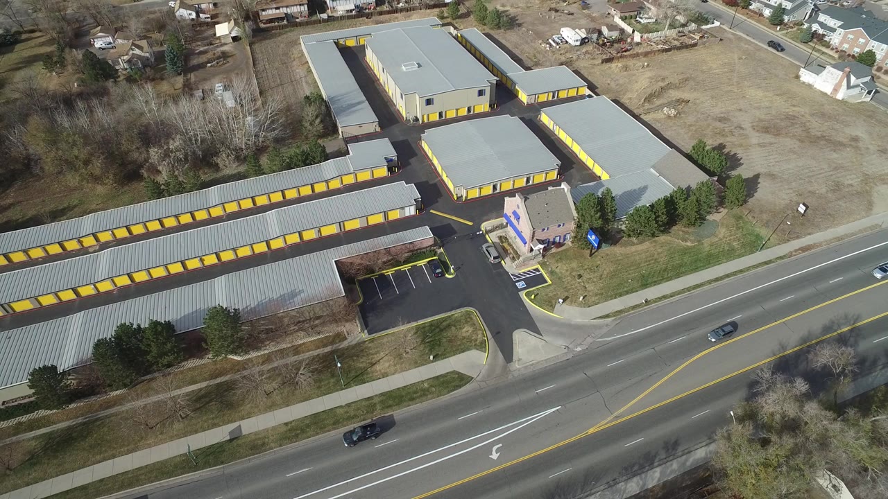 Aerial view of long yellow-doored buildings beside a multi-lane road.