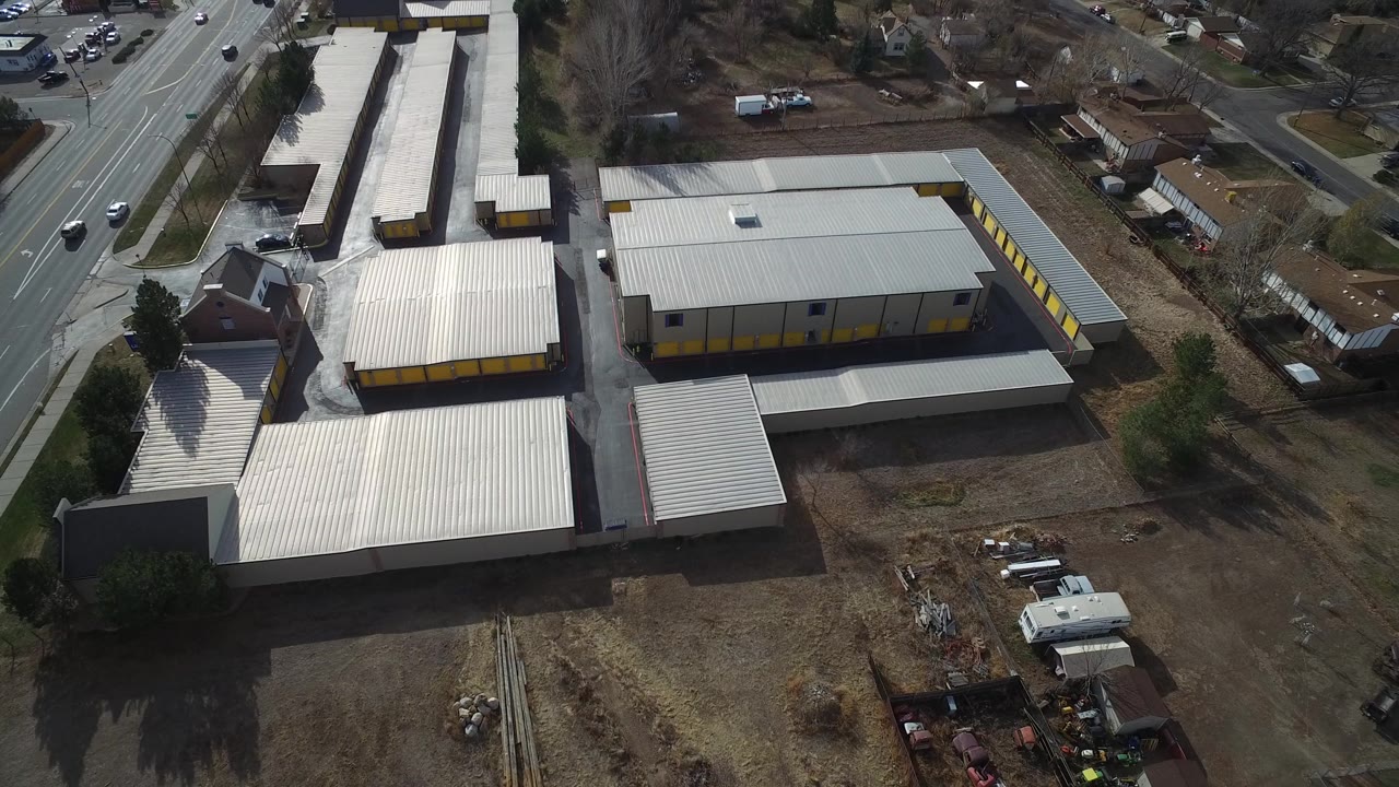 Drone view of industrial roofs and roads with cars passing.