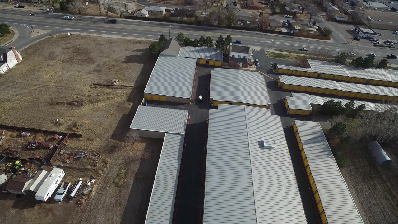 Aerial view of metal-roofed buildings beside a highway and vacant lot.
