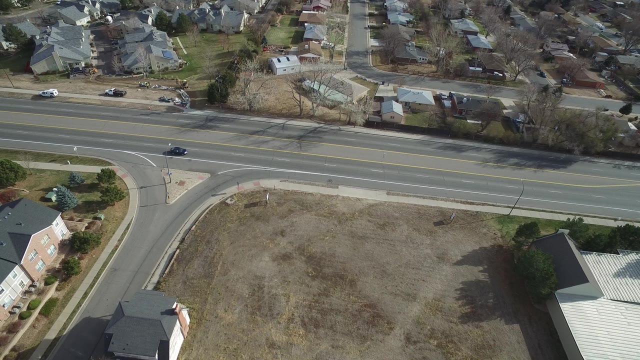 High angle view of a road intersection, lot, and nearby homes.