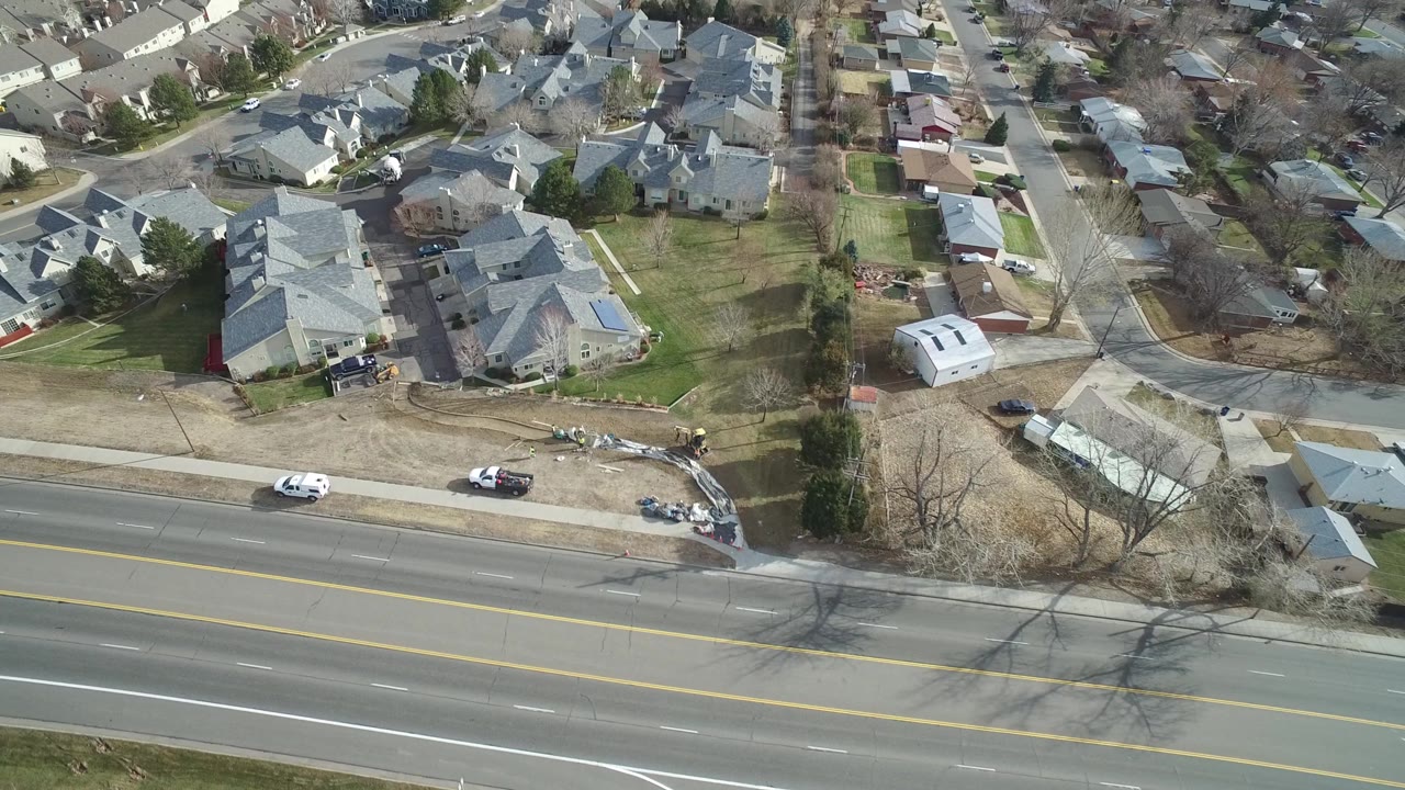 Bird's-eye frame of Westminster, Colorado houses and backyards, with the road still visible at the bottom and no visible people in the streets or yards.